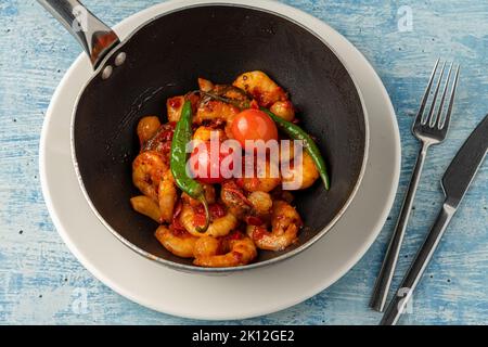 Cocotte de crevettes avec tomates, ail et poivrons dans un wok noir Banque D'Images