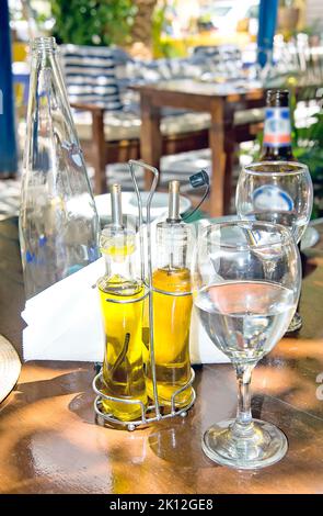 La vie de la taverne grecque avec verre d'eau froide, bouteille de verre vide et huile d'olive Banque D'Images