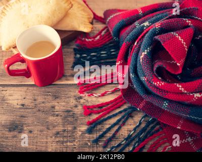 Couverture rouge et noire chaleureuse, tasse de café chaud et tartes fraîchement cuites pour une journée froide d'hiver, espace copie Banque D'Images