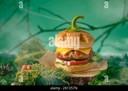 Hamburger d'Halloween en forme de lanterne de citrouille dans une forêt mystérieuse. Cheeseburger effrayant lors de la fête d'halloween. Banque D'Images