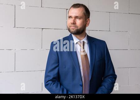 Un homme d'affaires arabe élégant et confiant sur fond de mur blanc de briques de la ville, un espace de copie. Portrait d'un beau homme d'affaires mature Banque D'Images