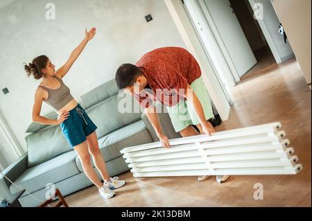 Cohabitation. Un jeune couple marié installe une poutre décorative dans son nouvel appartement Banque D'Images