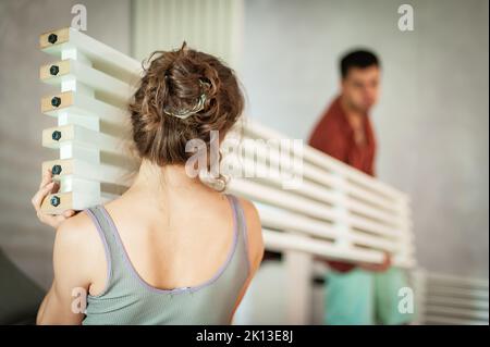 Cohabitation. Un jeune couple marié installe une poutre décorative dans son nouvel appartement Banque D'Images