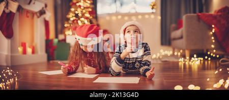 Les enfants sont à l'intérieur et écrivent des lettres pour le Père Noël. Banque D'Images