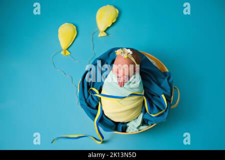 Nouveau-né ukrainien dans le studio patriotique bleu jaune couleurs pendant la guerre en Ukraine 2022. Un petit bébé, une fille dort sur un fond isolé Banque D'Images