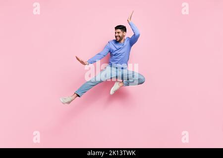 Photo pleine longueur de cool fort gars habillé pull-over bleu saut haute pratique karaté isolé couleur rose fond Banque D'Images