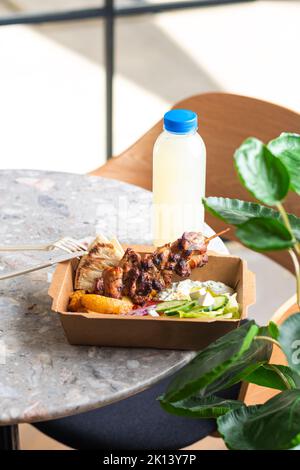 Livraison rapide de la nourriture.cuisine grecque souvlaki, salade et gyros à emporter au restaurant fastfood servi dans des assiettes en papier recyclables sur la table Banque D'Images