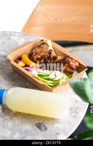 Livraison rapide de la nourriture.cuisine grecque souvlaki, salade et gyros à emporter au restaurant fastfood servi dans des assiettes en papier recyclables sur la table Banque D'Images