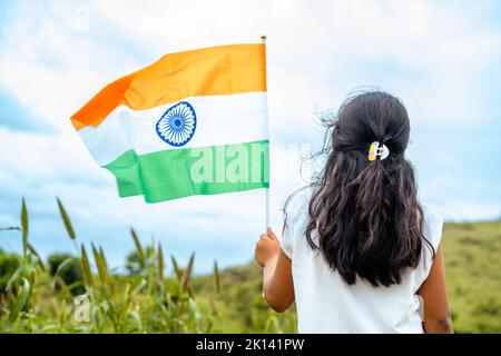 Vue arrière de la petite fille de course à pied avec drapeau indien en main - concept de patriotisme, célébration de la fête de la république et liberté Banque D'Images