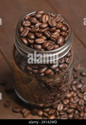 Grains de café dans un pot de maçon en verre sur bois Banque D'Images