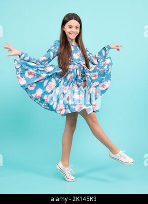 Pleine longueur surjoyée adolescent fille 12 13 14 ans saut vieux isolé sur fond bleu studio. Un saut amusant. Enfant en robe de mouvement d'été. Banque D'Images