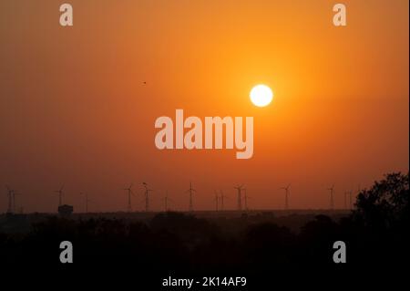 Soleil levant sur le désert de Thar, Jaisalmer, Rajasthan, Inde. Moulins à vent à horizon lointain. Banque D'Images