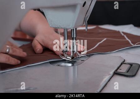 Les coutures de couturière à la machine à coudre filent le tissu. Mains des femmes Banque D'Images