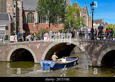 Amsterdam, pays-Bas - août 2022 : petit bateau à moteur sur le point de passer sous un pont de canal plein de touristes visitant la ville de trhe Banque D'Images