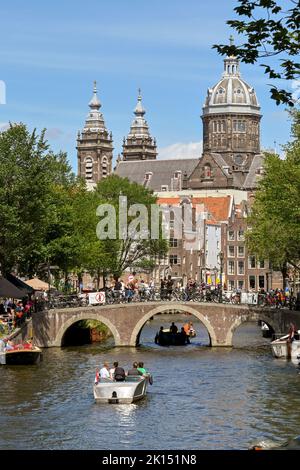 Amsterdam, pays-Bas - août 2022 : petit bateau à moteur sur le point de passer sous un pont de canal plein de touristes visitant la ville de trhe Banque D'Images