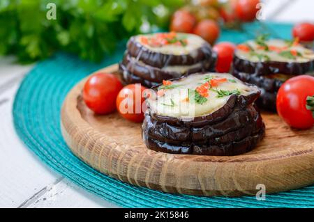 Aubergine cuite au fromage mozzarella, tomates sur une assiette en bois, gros plan. Recette végétarienne Banque D'Images