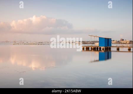 Jetée en bois et bâtiment reflétant dans une mer Méditerranée calme, un matin d'été Banque D'Images