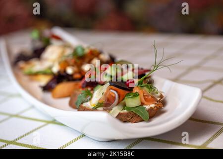 Bruschetta avec diverses garnitures, une variété de petits sandwiches sur une assiette blanche. Banque D'Images