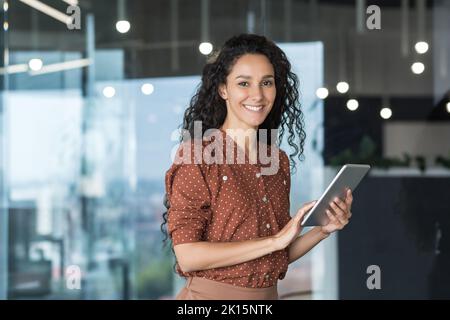 Jeune et réussie femme programmeur, portrait d'une femme ingénieur avec un employé de démarrage d'ordinateur de tablette travaillant à l'intérieur du bâtiment de bureau utilisant une tablette pour tester des applications souriant regardant la caméra. Banque D'Images