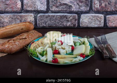 Assiette de fromages sur une table sombre. Plusieurs sortes de fromage sur une assiette Banque D'Images