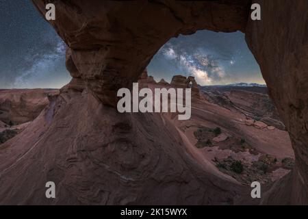 Vue à couper le souffle de Delicate Arch, situé près d'un canyon agitée contre une voie lactée dans le ciel nocturne du parc national d'Arches, dans l'Utah, aux États-Unis Banque D'Images