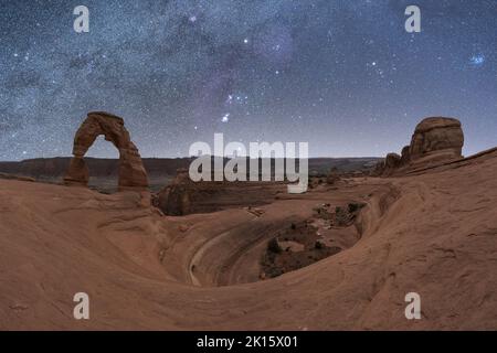 Vue à couper le souffle de Delicate Arch, situé près d'un canyon agitée contre une voie lactée dans le ciel nocturne du parc national d'Arches, dans l'Utah, aux États-Unis Banque D'Images