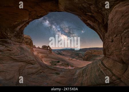 Vue à couper le souffle de Delicate Arch, situé près d'un canyon agitée contre une voie lactée dans le ciel nocturne du parc national d'Arches, dans l'Utah, aux États-Unis Banque D'Images