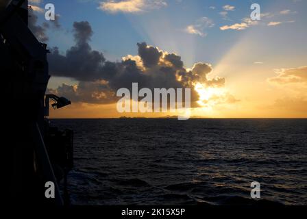 Coucher de soleil spectaculaire en mer, dans les Caraïbes, avec les rayons du soleil venant de derrière un nuage Banque D'Images