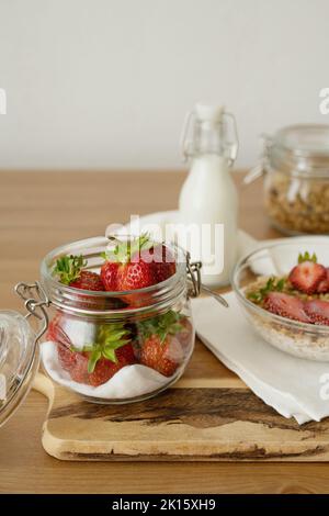 Des fraises fraîches et fraîches crues placées dans un pot en verre sur une table en bois à la lumière du jour dans la cuisine Banque D'Images