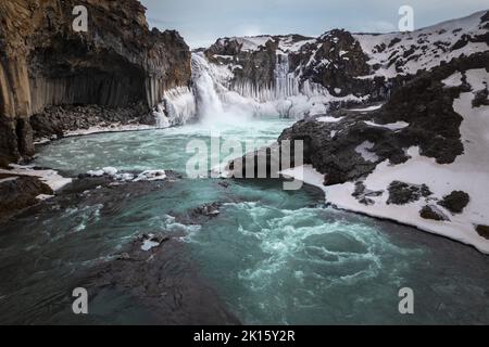 Vue pittoresque de drone de la cascade d'Aldeyjarfoss tombant d'une falaise de neige rugueuse contre ciel nuageux en soirée en hiver en Islande Banque D'Images