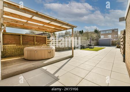 Arrière-cour d'une maison avec toit transparent et piscine portable à côté d'autres maisons alignées sous un ciel bleu nuageux Banque D'Images