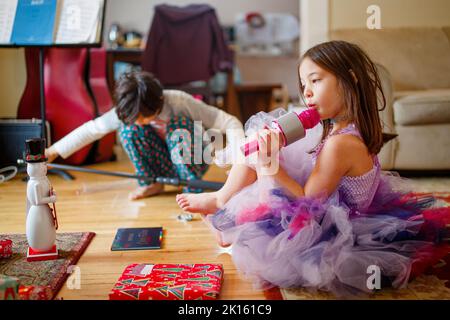 Petite fille en costume et frère jouent avec des cadeaux de noël Banque D'Images