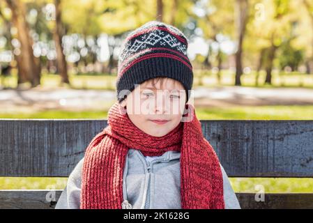 Enfant attentionné portant un chapeau en laine et un foulard dans le parc Banque D'Images