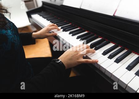 Vue latérale des mains de femmes jouant du piano en lisant de la musique de fond. Mise au point sélective Banque D'Images
