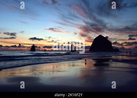 Un coucher de soleil coloré à Cannon Beach, Oregon, avec Haystack Rock dans Silhouette. Banque D'Images