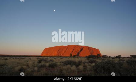 Une vue magnifique sur Uluru au coucher du soleil. Au coucher du soleil, l'incroyable Ayers Rock passe du rouge à une incroyable nuance d'orange vif. Banque D'Images