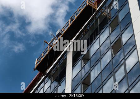 Plate-forme suspendue sans ouvriers sur une façade en verre et en acier de gratte-ciel Banque D'Images