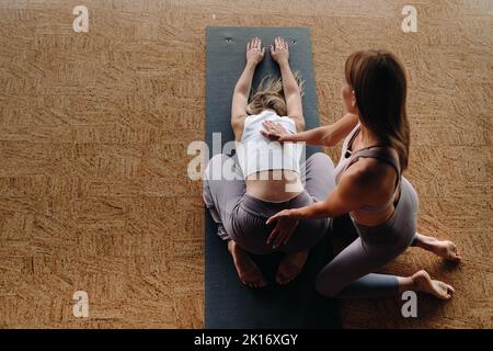 Exercices de yoga. Un entraîneur personnel enseigne à une femme des cours de yoga dans la salle de gym Banque D'Images