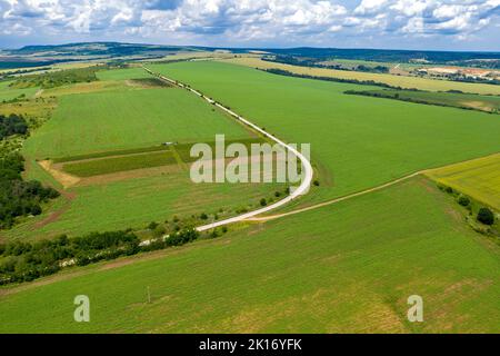 Vue aérienne incroyable depuis un drone de grande courbe de route, de campagne, de champs et de ciel nuageux Banque D'Images