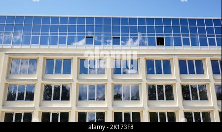 Les nuages se reflètent dans les fenêtres d'un immeuble de bureaux moderne. Extérieur d'un bâtiment moderne par temps ensoleillé avec un ciel bleu Banque D'Images