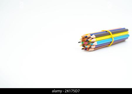 Crayons de couleur bois rassemblés dans un paquet avec une bande de caoutchouc sur un fond blanc avec un point (plomb) en évidence Banque D'Images