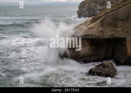 Vagues éclaboussant sur des rochers à tunnel Beach, Dunedin. Photo prise à une vitesse d'obturation lente montrant le mouvement des vagues. Banque D'Images