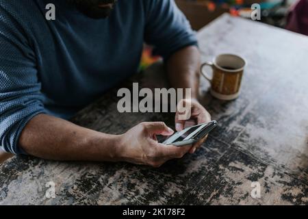 Homme assis à la table et utilisant le téléphone Banque D'Images