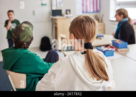 Vue arrière d'une fille assise dans une salle de classe Banque D'Images