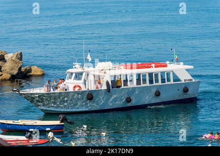 TELLARO, ITALIE - 19 JUILLET 2022 : bateau de ferry blanc avec un groupe de touristes dans le petit port de l'ancien village de Tellaro, Lerici, Golfe de la Spez Banque D'Images