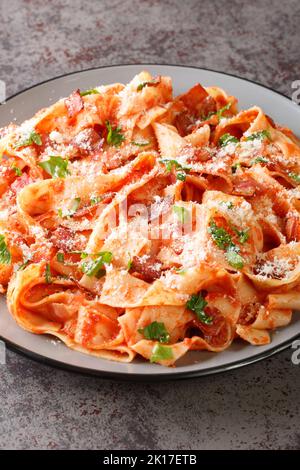 La Pappardelle alla Fiesolana est un plat classique italien confortable composé de pâtes, bacon, oignons, tomates et parmesan dans l'assiette de la table. Verti Banque D'Images