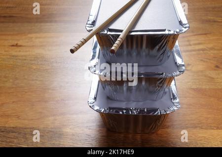 Pile de feuille d'argent plateaux à emporter avec des baguettes placées sur le dessus Banque D'Images