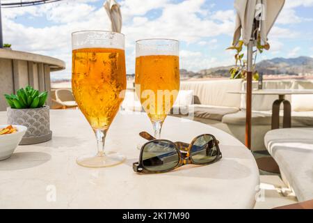 Deux verres avec bière et lunettes de soleil sur une table sur un toit-terrasse, restaurant, Espagne. Banque D'Images