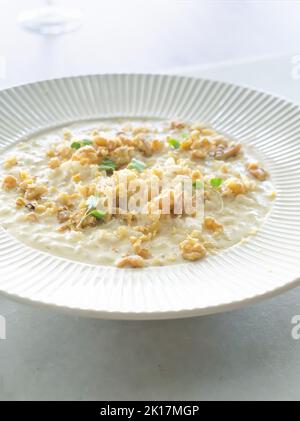 Risotto délicieux et crémeux, accompagné de fromage et de noix sur une assiette blanche. Vue de dessus et gros plan Banque D'Images