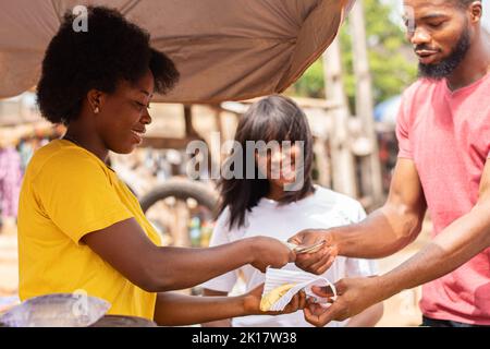 les gens qui achètent du plantain rôti auprès d'un vendeur de bord de route Banque D'Images